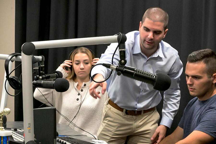 A groups of students with a staff member using radio equipment in the department media lab