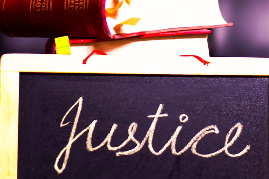 A chalkboard with the word "justice" written on it and a book sitting on top of it.