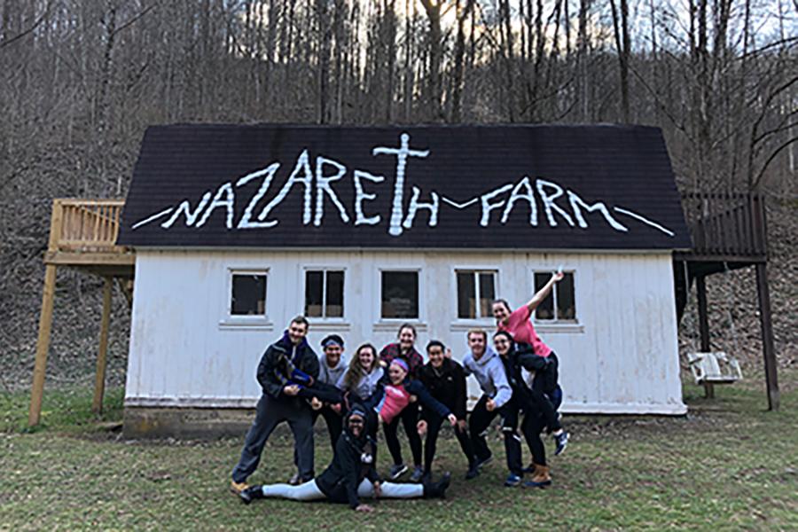 A group of students stand together in front of a building at Nazareth Farm in West Virginia.