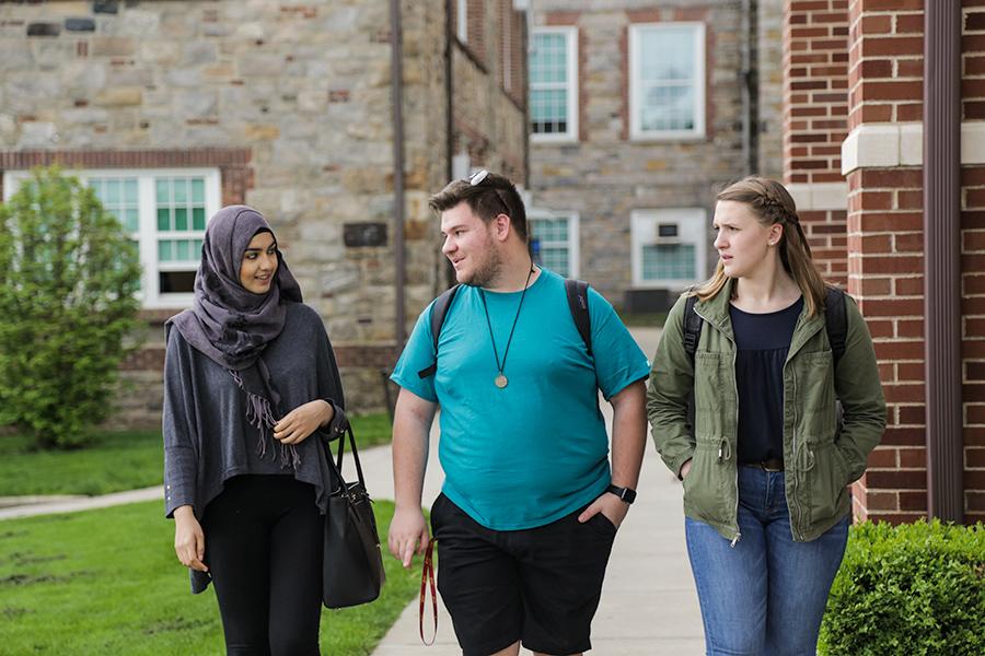 Three Diversity and Social Welfare students walk side by side next to East Hall.
