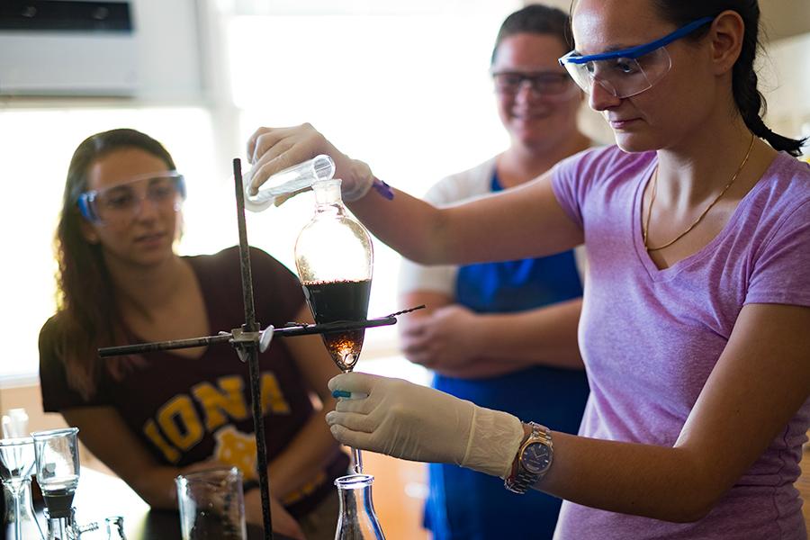 Three students are working in a biochemisty lab while wearing goggles