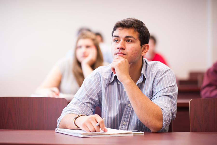 A student rests his chin in his hand during a lecture for an psychology class.