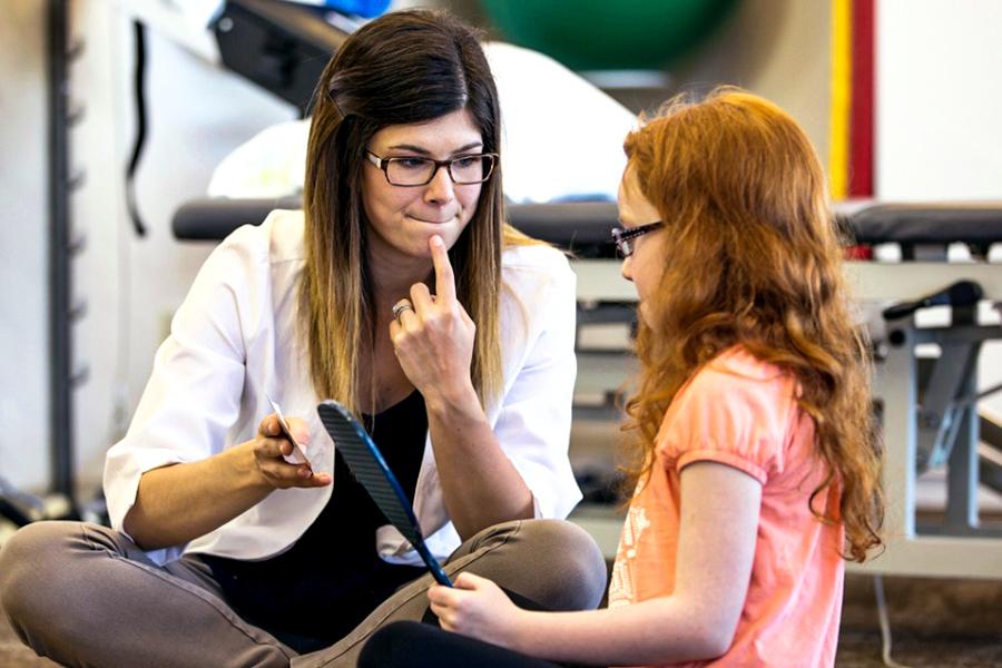 A speech therapist works with a young patient.