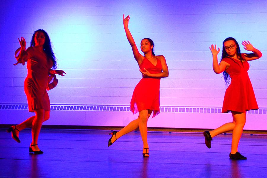 Three dancers perform in red dresses.