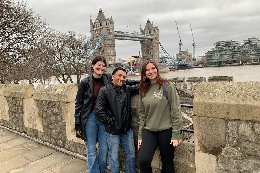 Three students smile with London Bridge in the background.
