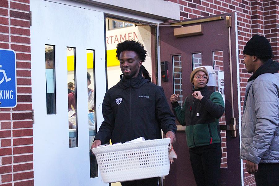 An athlete carries a Thanksgiving basket to the vans.