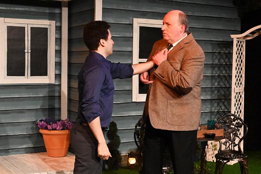 A man in a blue shirt grabs the collar in anger of a man in a suit.