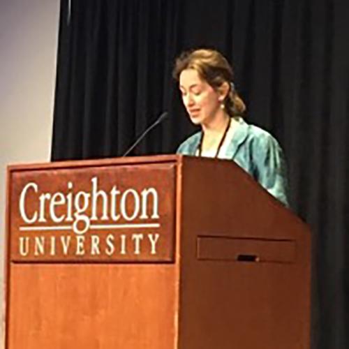 Dr. Erin Lothes stands and speaks at a podium at Creighton University.