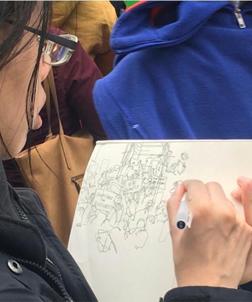 A young person sketches a picture of climate change demonstrators.