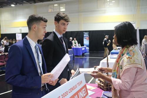 Two students in suits speak with a representative at the Career Expo.