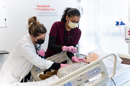 Nursing students work at a bedside simulation.