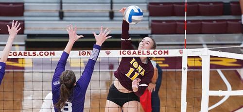 A member of the women's volleyball team spikes the ball.