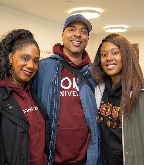 A family of three in Iona gear at the 2023 Family Weekend.