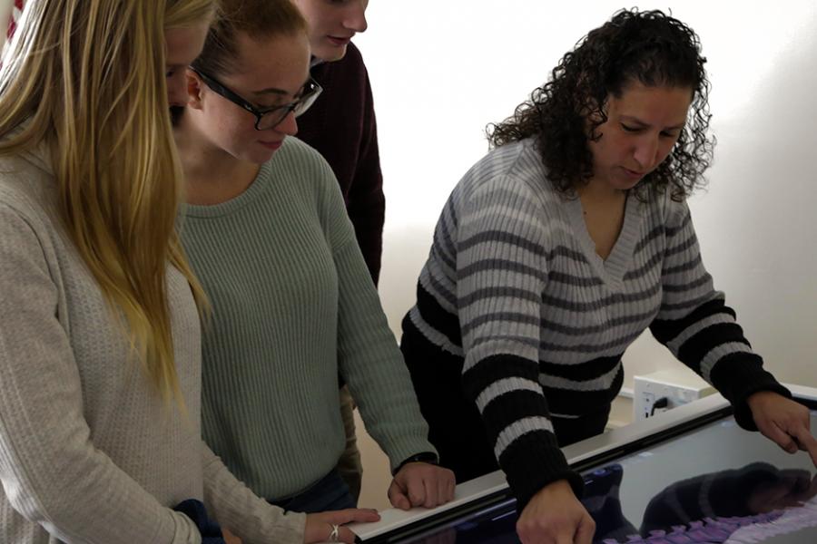 A professor shows some biochemistry students a 3D model of a human spine.