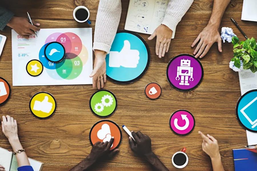 People collaborate on a table covered with circular marketing symbols.