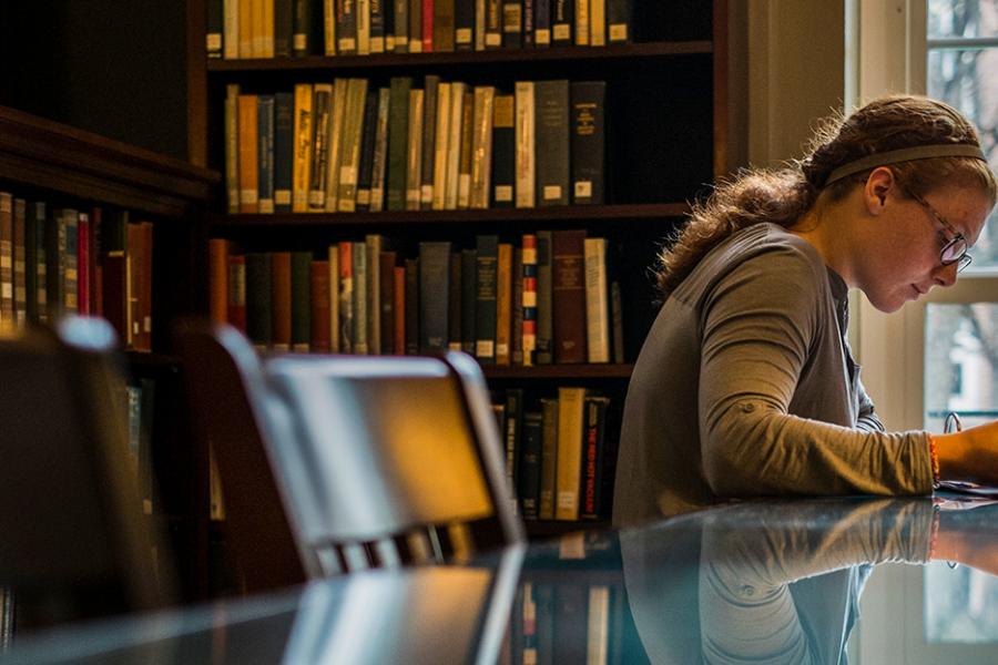 A female student studies by herself in the library.