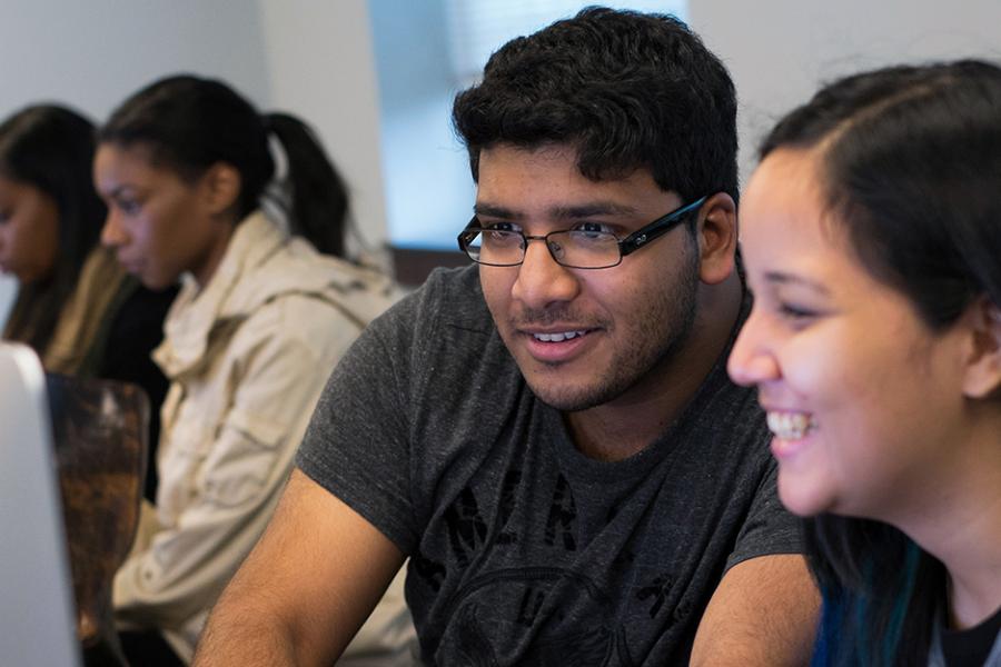 Two students work enthusiastically at an iMac in the computer lab.