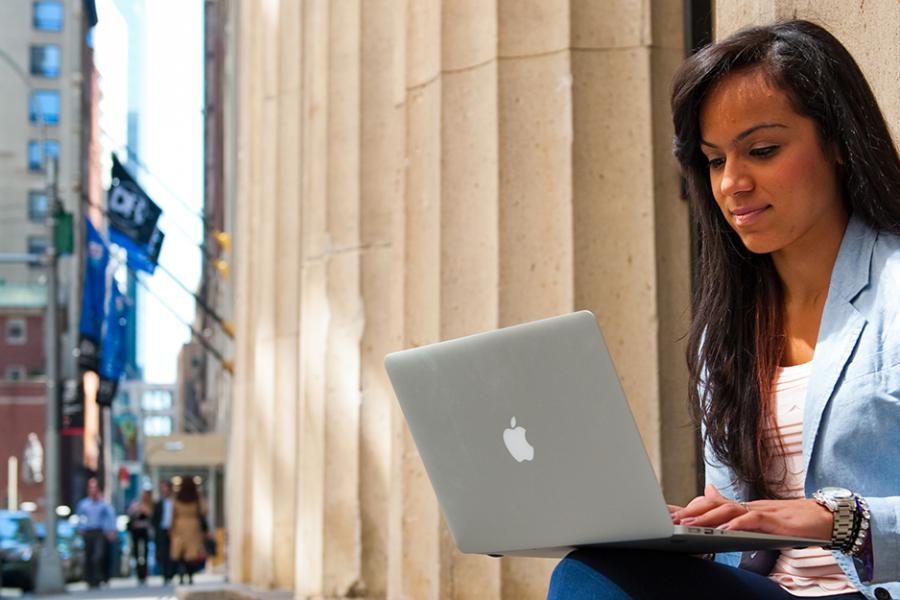 A student sits in New York City and works on her laptop.