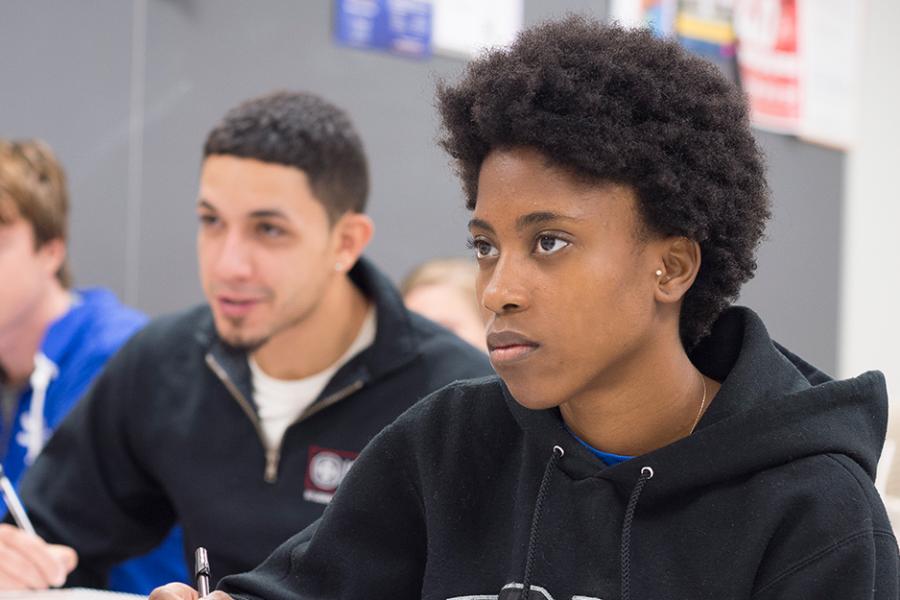 A female student takes notes in a class for her economics class.