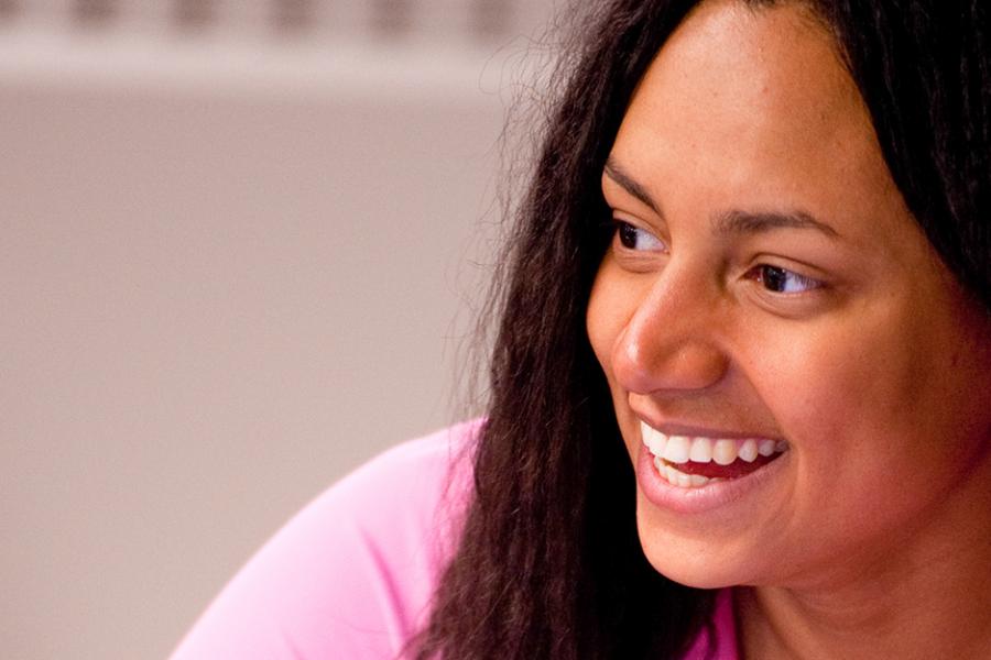 A student in a pink hoodie smiles brightly in a marketing class.