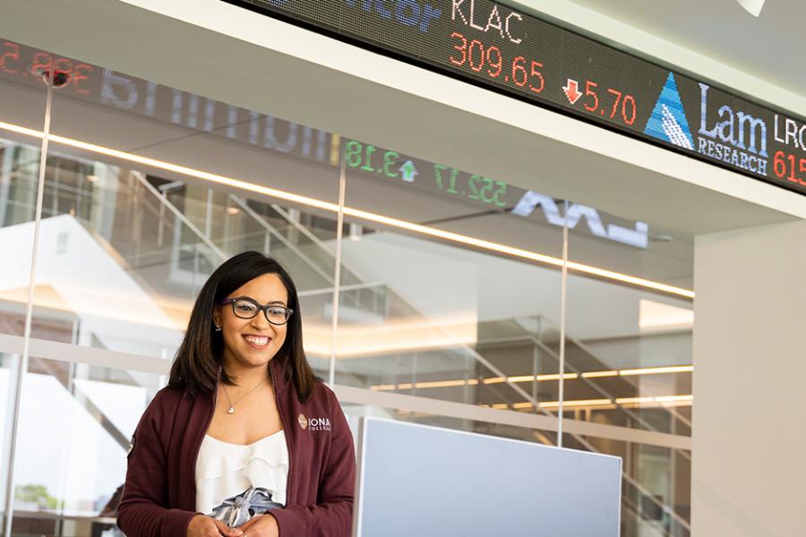 A student stands in front of the ticker and does a presentation in the LaPenta School of Business trading floor.