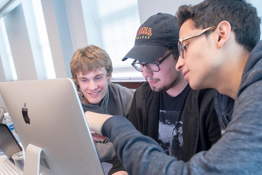 Three students work together at a computer for their minor in business analytics.