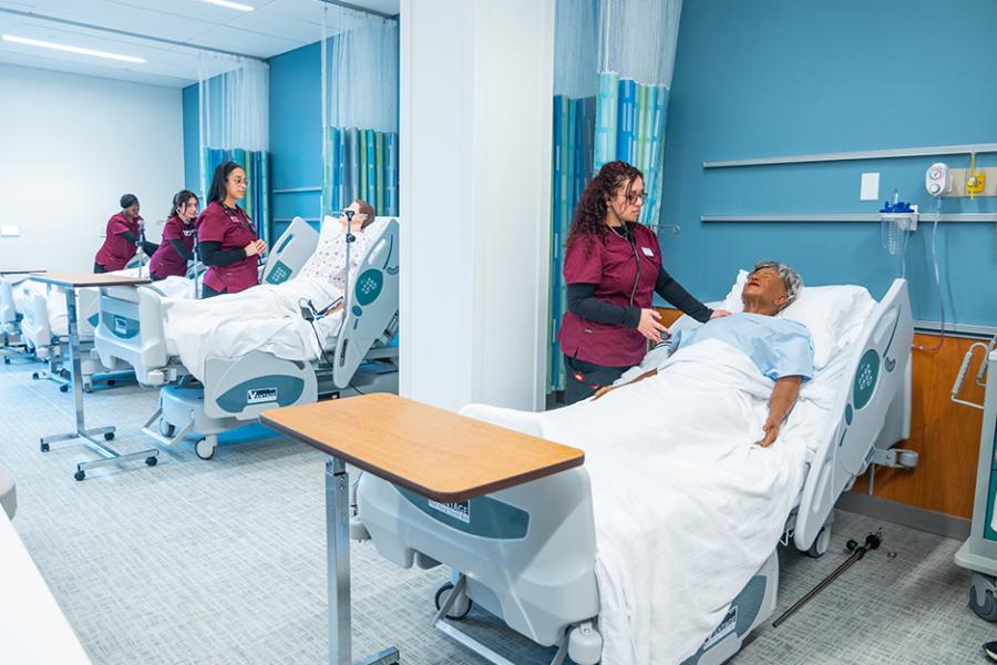 Four students in the accelerated nursing program work in the simulation lab.