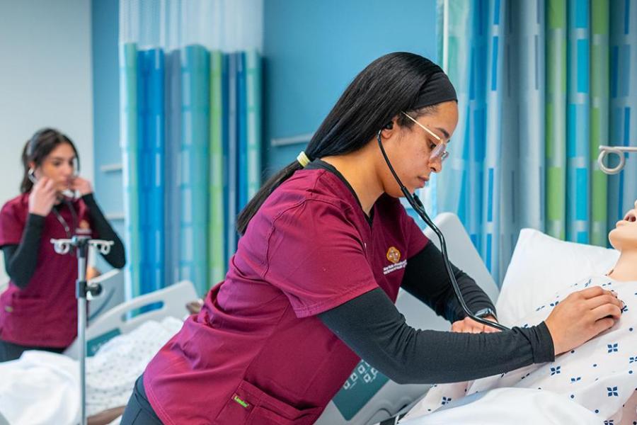 Three nurses in the simulation lab work with mannequins