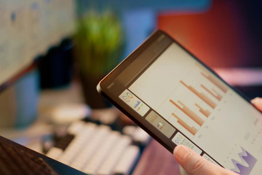 A person working on various dashboards with a computer and a tablet.