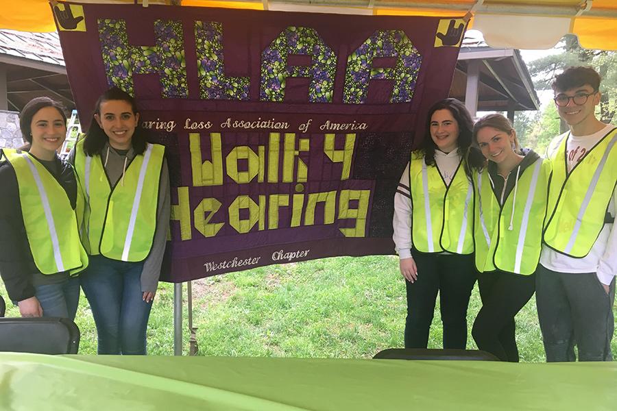 Iona University ASL club standing in front of the HLAA Walk for Hearing sign.