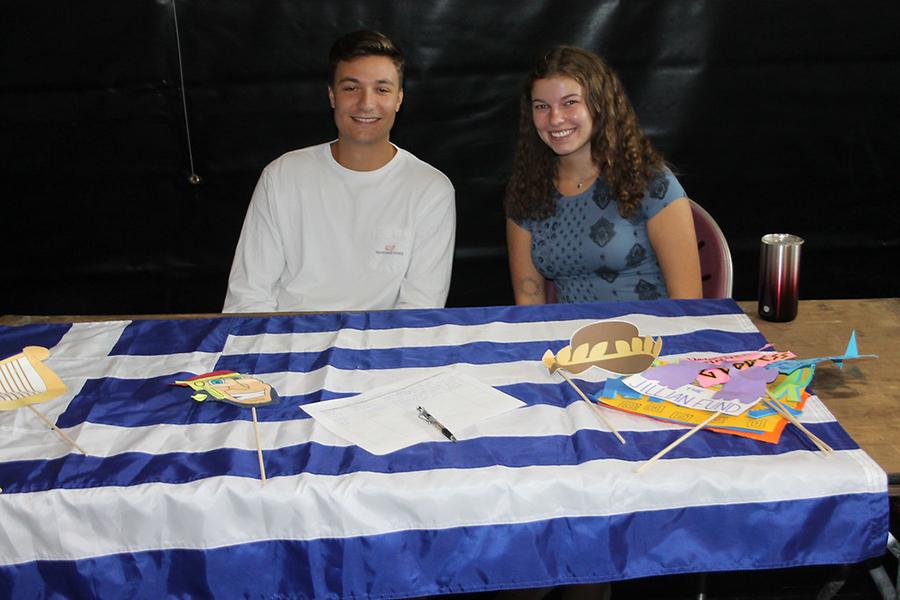 Two members of the Greek Sulture Society recruit members at a club table.