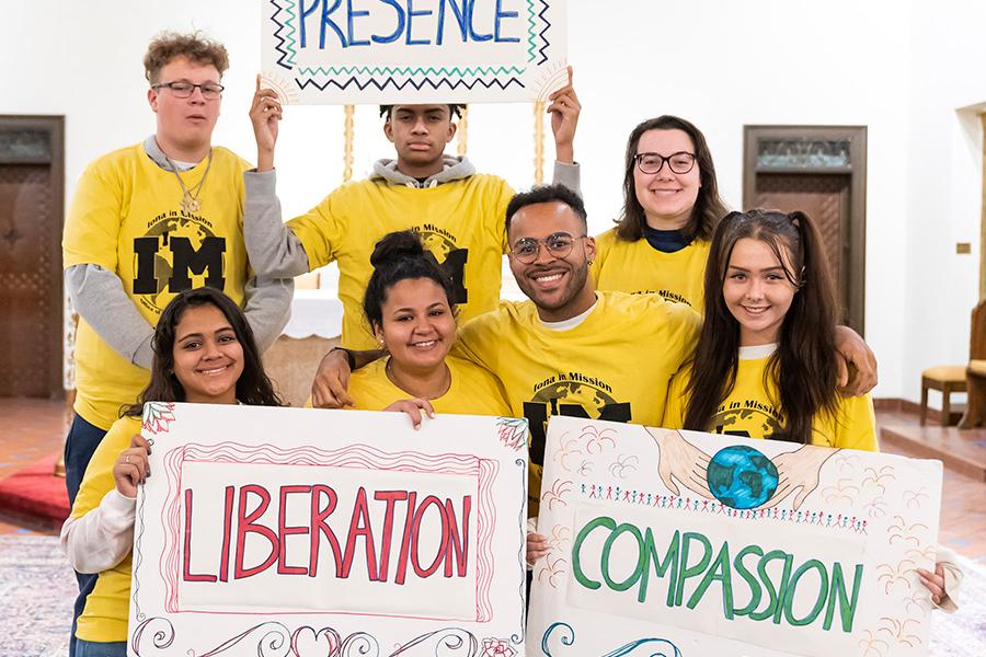 Mission and Ministry students hold up signs that say Presence, Liberation and Compassion.