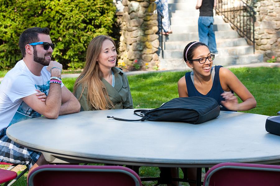 Students sit a table and share a few laughs at a Mission and Ministry hospitality supper.