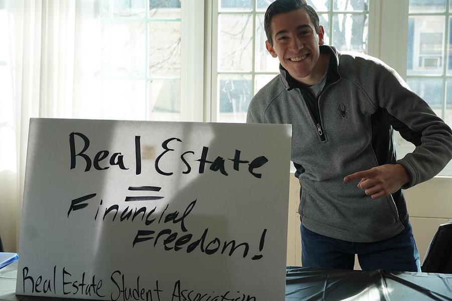 The president of the Real Estate Association posing with his sign for the club.