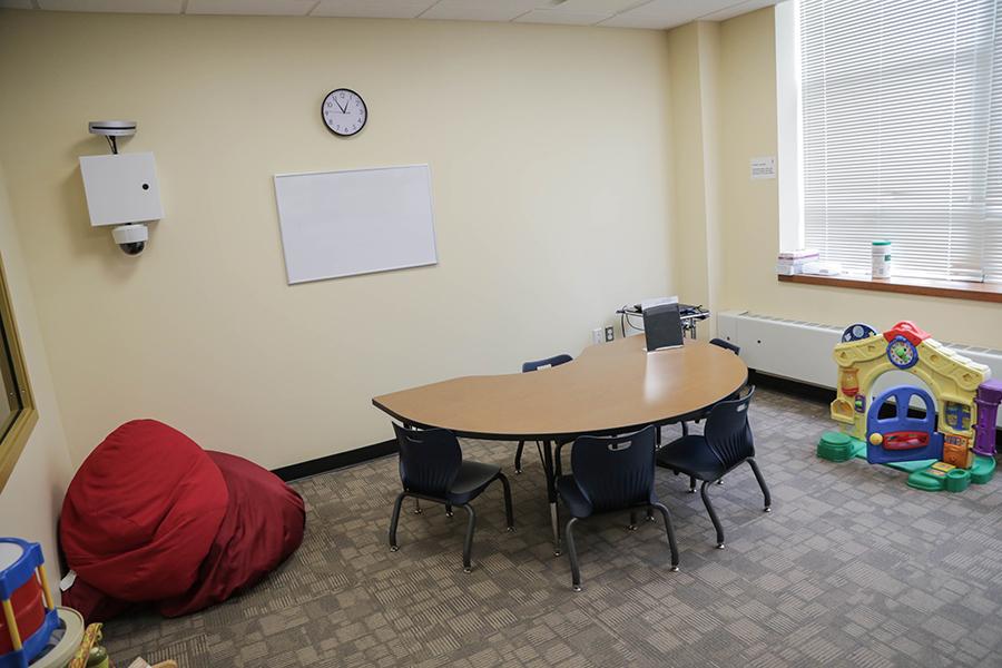 The treatment space for children has a small table with four small chairs, some red bean bags, and a variety of toys.