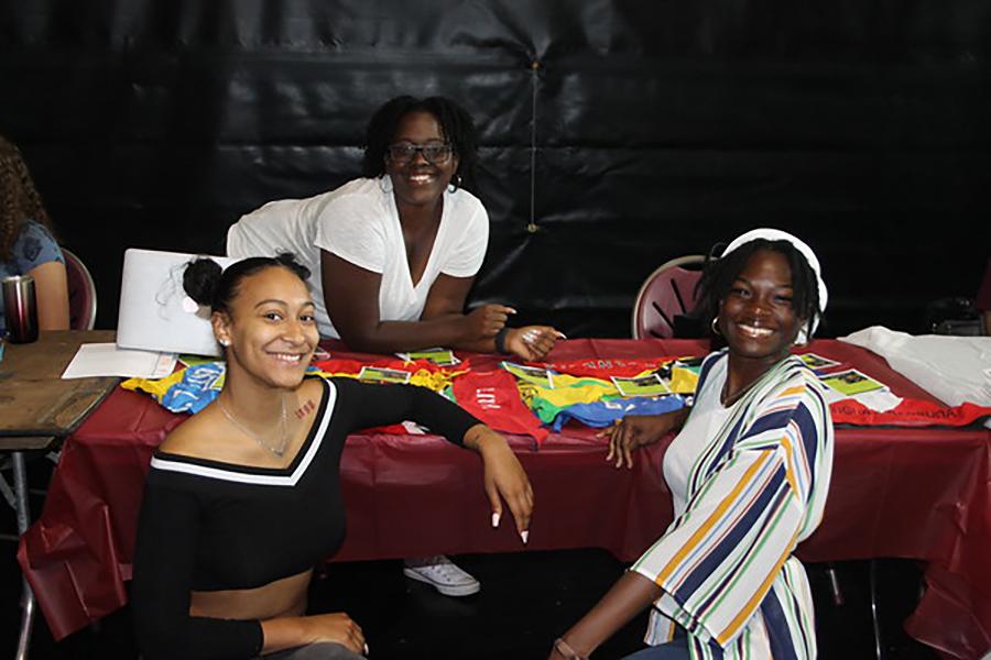 Three students smile at their club table at the involvement fair.