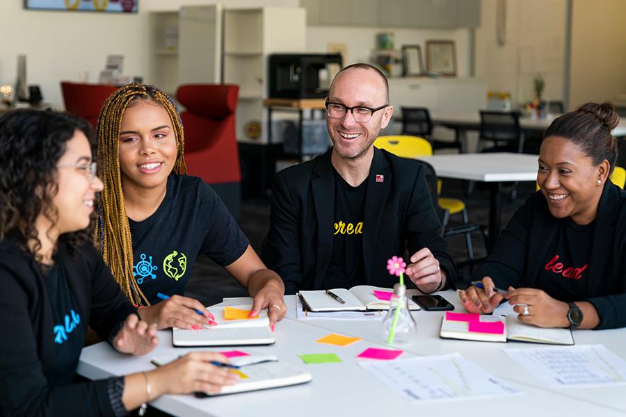 Members of the Hynes Institute staff sit at a table with a student and have a brainstorming session.