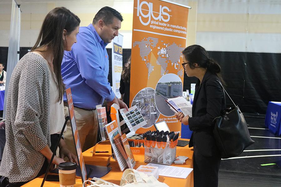 A student chats with 2 representatives from Igus at the career fair.