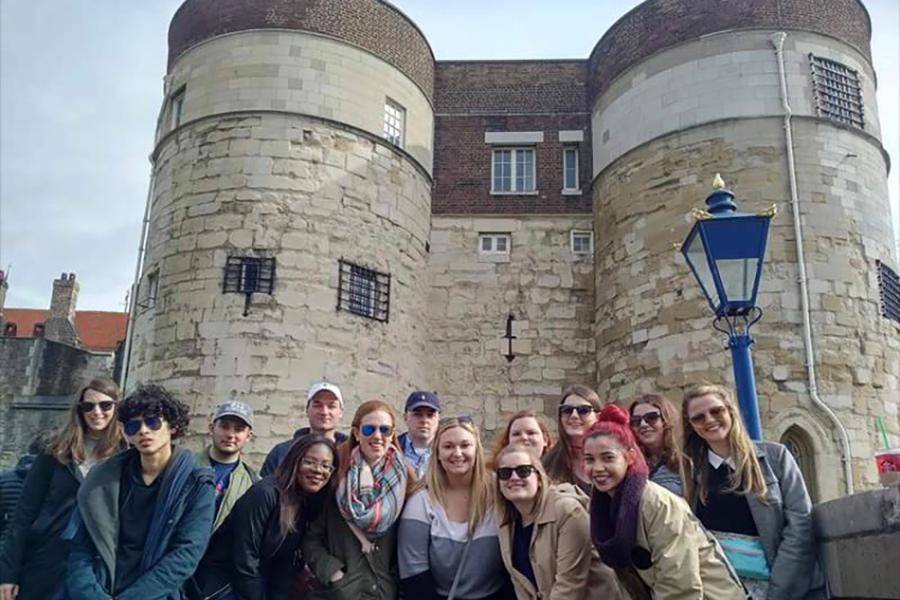 Iona students pose in front of a castle like building in London, England.