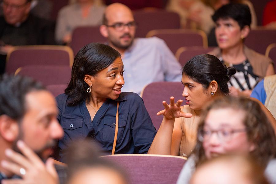 Two staff members discuss something at a meeting.