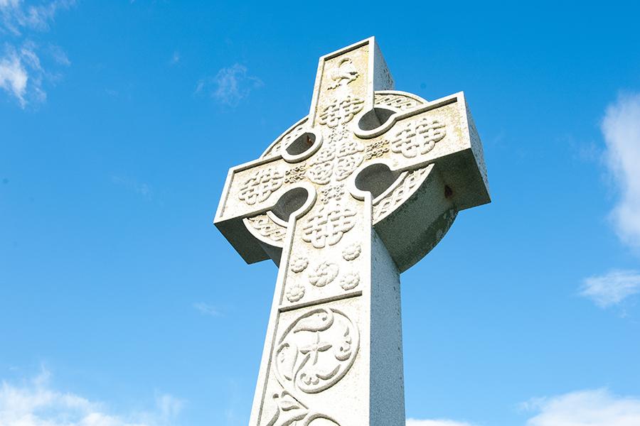 The Celtic Cross against a blue sky with a few white clouds.