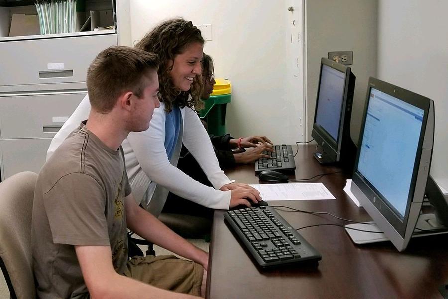 Nicole from the advising center helps a student create his schedule at one of their computer work stations.