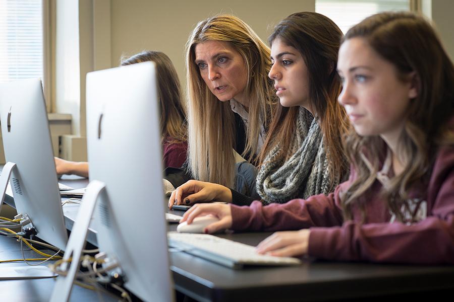 A computer science professor assists a computer science major with her work.