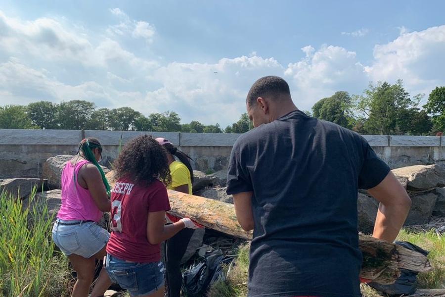 Iona students and other volunteers help to clear a log from a field.