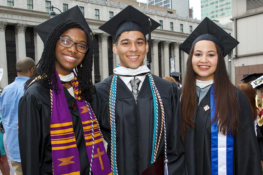 Three Iona graduates pose in their gowns outside of the commencement ceremony.