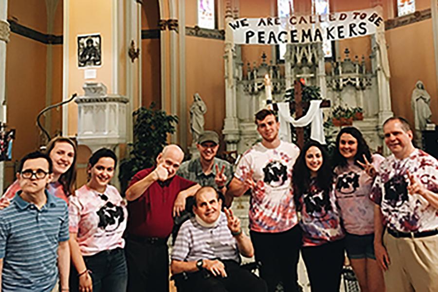 Students pose in a church with members of the L'Arche Syracuse community.