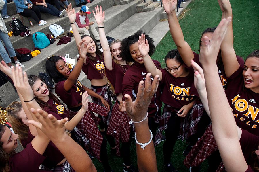 Members of the Iona Dance team raise their arms in victory at homecoming.