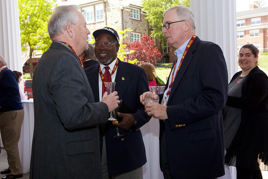 Three men enjoy cocktails, smile and catch up during the reunion weekend.