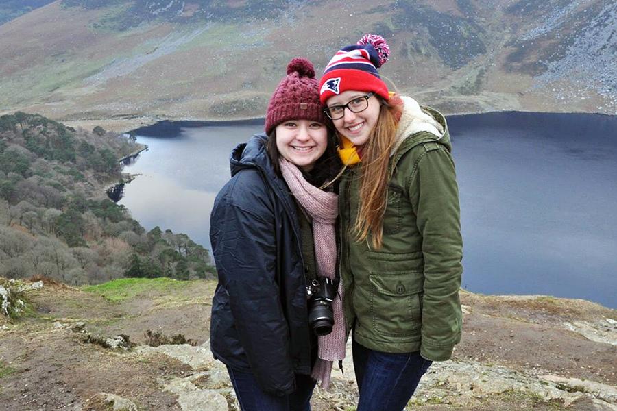 Two female students pose in front of a cliff.