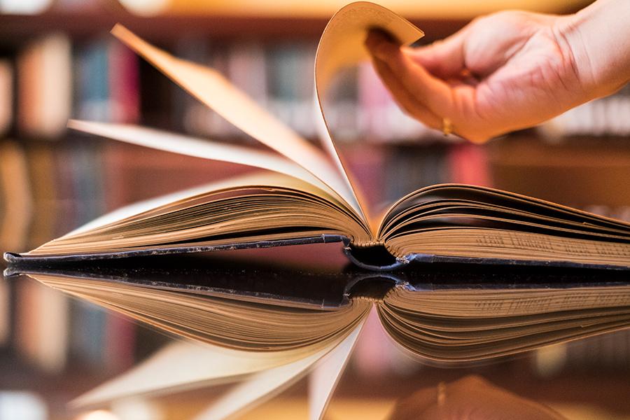 Someone flips the pages of a book on a table in the library.